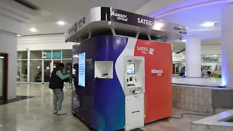 Kiosco de información minimalista con pantalla táctil y mostrador de atención, en un evento o convención.