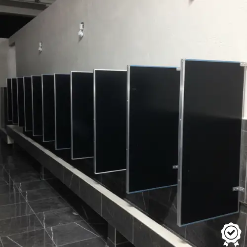 Mamparas Negras Hidalgo Series de mamparas sanitarias de color negro instaladas en un baño público moderno con piso de mármol oscuro, ideales para negocios y espacios comerciales en Pachuca, Hidalgo y sus alrededores.