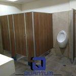 Cubículos sanitarios económicos de Panealart Melamínico con acabado tipo madera y perfiles de aluminio instalados en un baño institucional en Tlajomulco de Zúñiga, Jalisco.