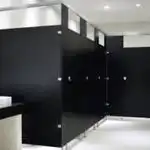 Instalación de mamparas sanitarias de sólido fenólico en acabado negro, con diseño moderno y resistencia superior para baños de alto tráfico en la colonia Providencia, Guadalajara.