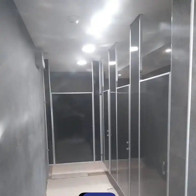 Mamparas sanitarias porcelanizadas en tono antracita con herrajes de aluminio, instaladas en baños ejecutivos de corporativo financiero en Polanco III Sección, Ciudad de México