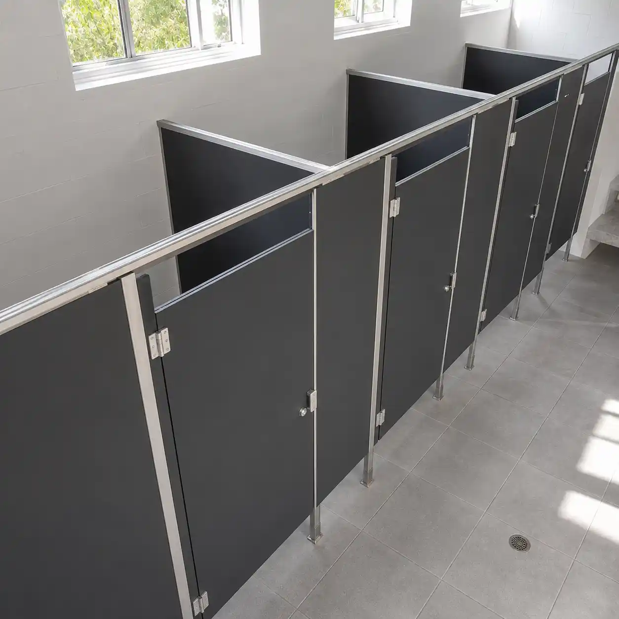 Instalación de mamparas sanitarias porcelanizadas en color gris oscuro con herrajes de acero inoxidable para módulo de baños corporativos en Cadereyta de Montes de Baz, Querétaro.